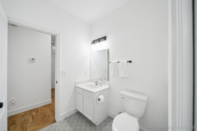 bathroom featuring vanity, toilet, baseboards, and wood finished floors