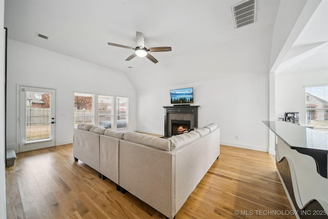 living area featuring a wealth of natural light, visible vents, light wood-type flooring, and a tile fireplace