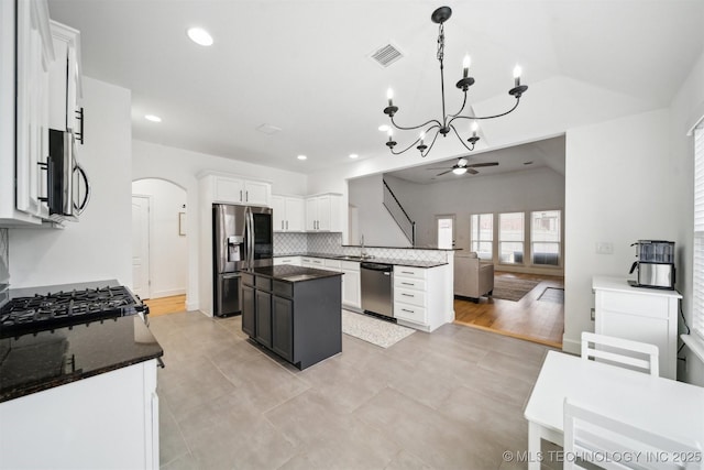 kitchen featuring visible vents, arched walkways, appliances with stainless steel finishes, ceiling fan with notable chandelier, and tasteful backsplash