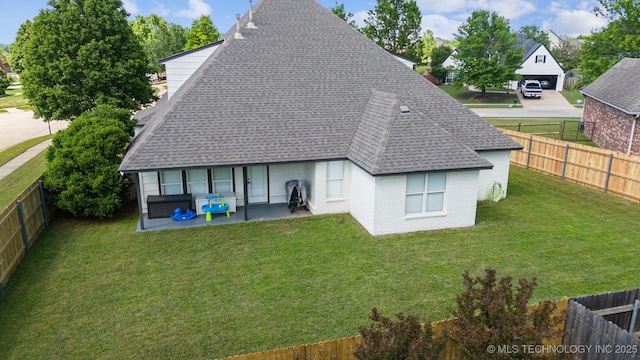 rear view of property featuring a shingled roof, brick siding, and a patio area
