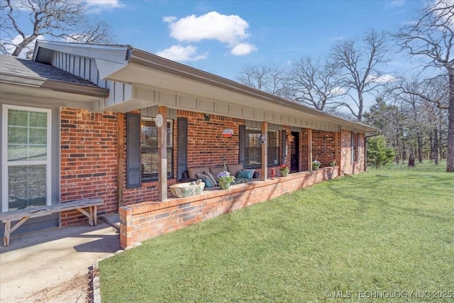 rear view of property with brick siding and a lawn