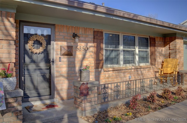 property entrance featuring brick siding and covered porch