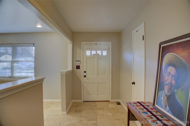 entryway with stone tile floors and baseboards