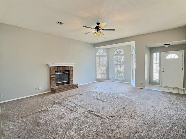 unfurnished living room featuring visible vents, a brick fireplace, baseboards, carpet flooring, and a ceiling fan