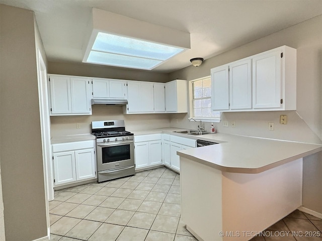 kitchen with a peninsula, a sink, light countertops, white cabinets, and gas range