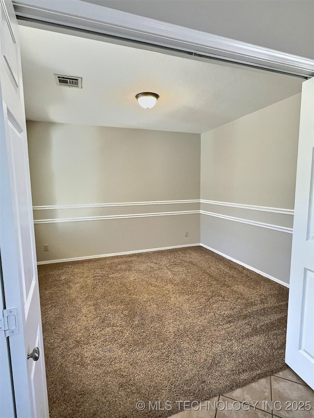 carpeted empty room with visible vents and baseboards