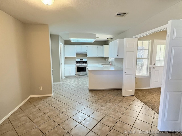 kitchen with visible vents, a sink, stainless steel range with gas cooktop, light countertops, and light tile patterned floors