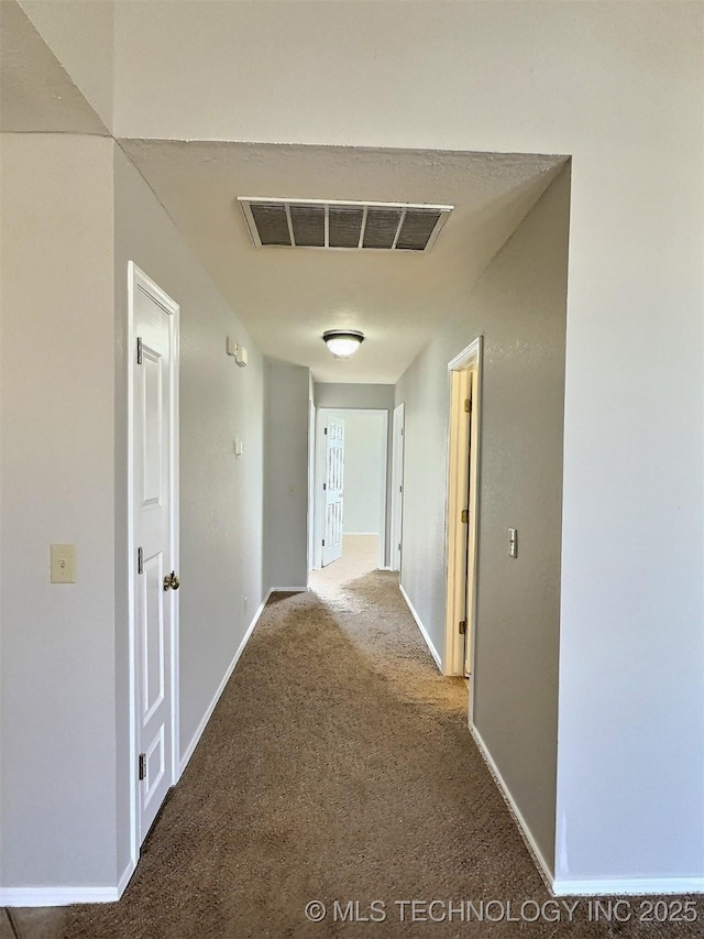 hall featuring visible vents, baseboards, and carpet