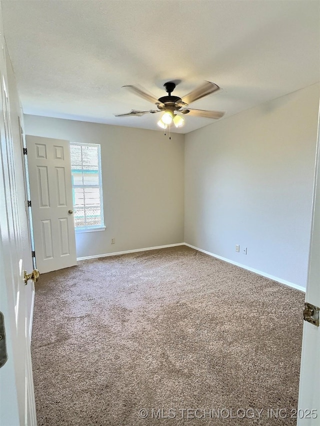 carpeted spare room featuring ceiling fan and baseboards