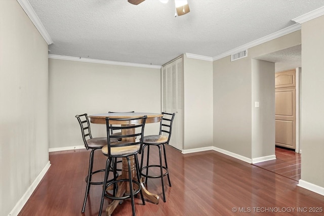 dining space with crown molding, wood finished floors, visible vents, and baseboards