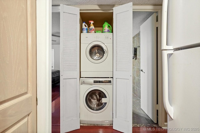 washroom featuring dark wood finished floors, stacked washer / dryer, a textured ceiling, and laundry area