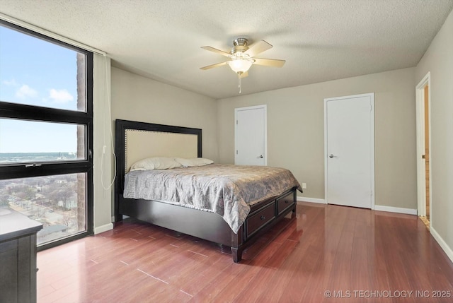 bedroom with ceiling fan, baseboards, a textured ceiling, and wood finished floors