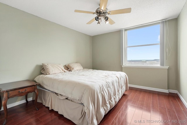 bedroom featuring ceiling fan, baseboards, a textured ceiling, and dark wood finished floors