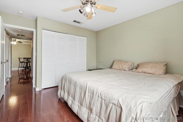 bedroom with visible vents, baseboards, dark wood finished floors, a closet, and a ceiling fan