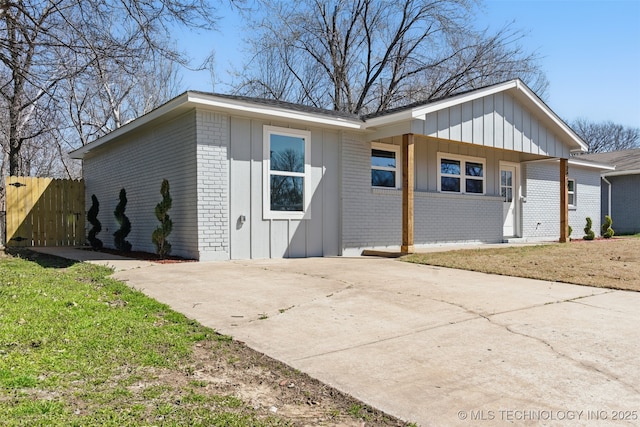 view of home's exterior with fence, brick siding, board and batten siding, and driveway