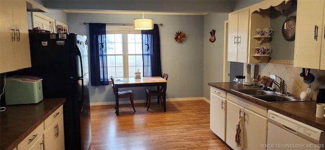 kitchen featuring light wood-type flooring, a sink, dark countertops, backsplash, and dishwasher