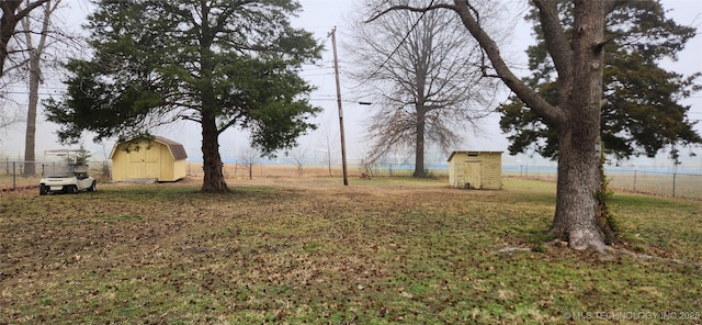 view of yard featuring an outbuilding, a storage shed, and fence