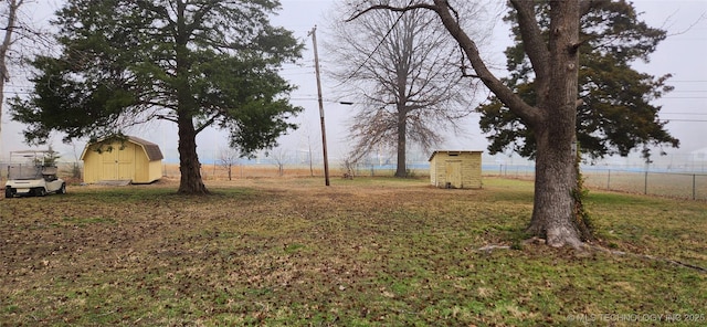 view of yard with an outbuilding, a storage unit, and fence