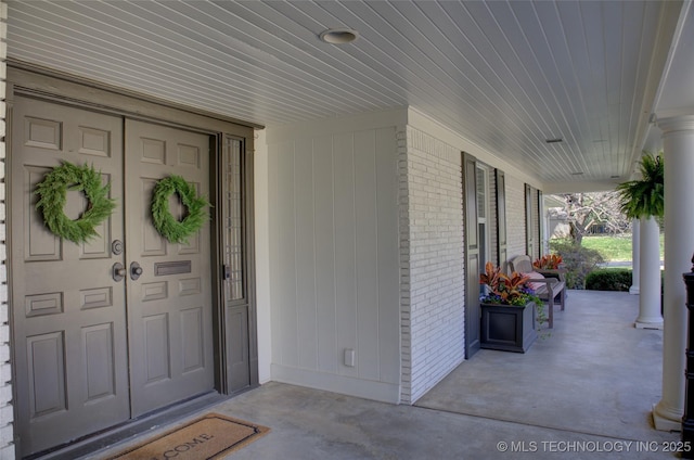 entrance to property featuring brick siding and covered porch