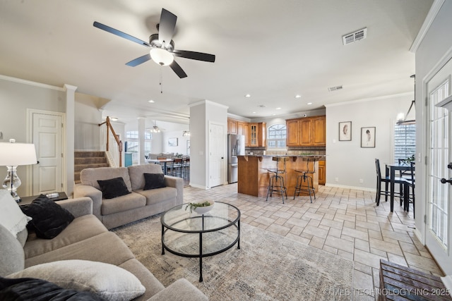 living room featuring stairs, stone tile floors, a healthy amount of sunlight, and visible vents