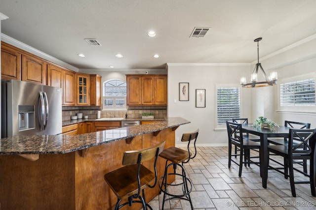 kitchen with tasteful backsplash, brown cabinetry, visible vents, and stainless steel appliances