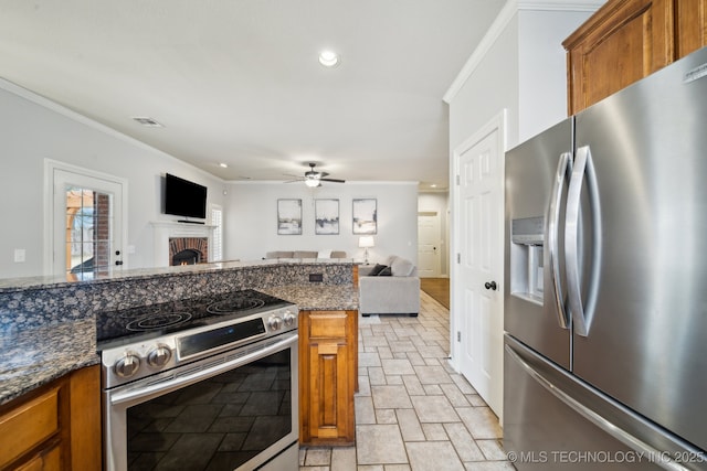 kitchen featuring brown cabinets, a fireplace, ornamental molding, appliances with stainless steel finishes, and open floor plan