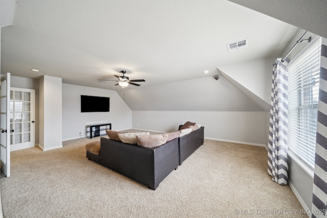 carpeted living room featuring visible vents, baseboards, lofted ceiling, and a ceiling fan