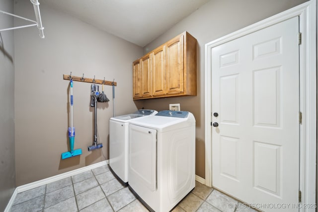 clothes washing area with cabinet space, light tile patterned floors, washer and dryer, and baseboards