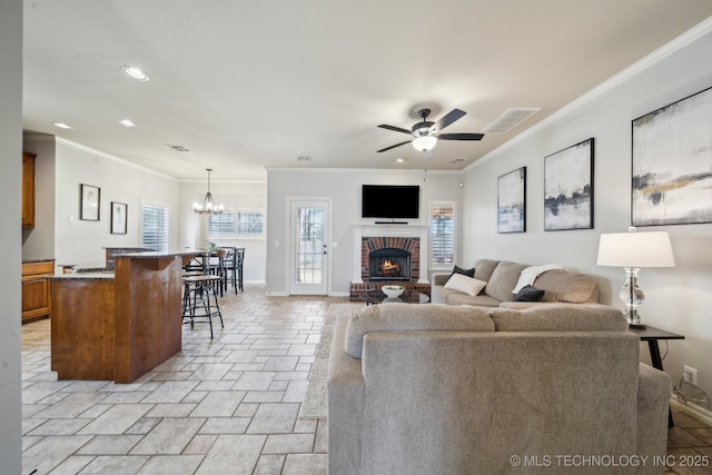 living area with crown molding, ceiling fan with notable chandelier, visible vents, and baseboards