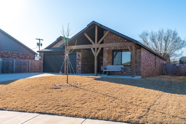 view of front facade featuring fence, a porch, an attached garage, concrete driveway, and brick siding