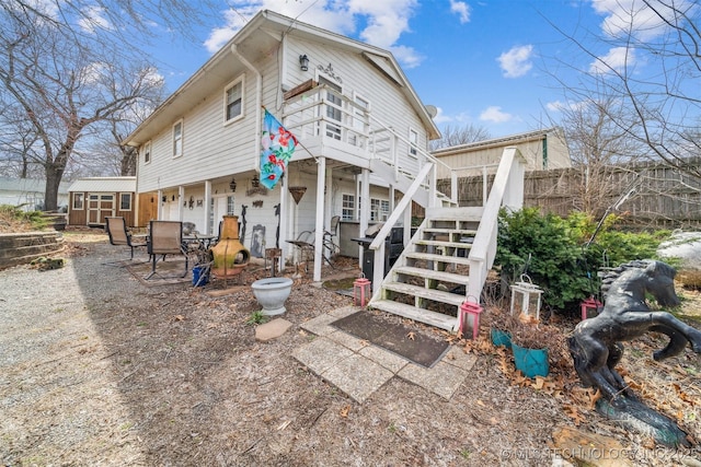 rear view of property with fence, a shed, a wooden deck, stairs, and an outdoor structure