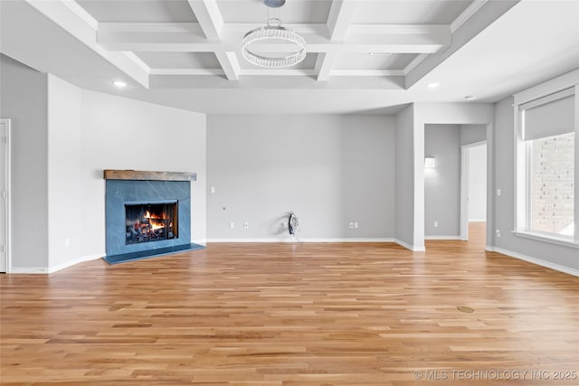 unfurnished living room featuring baseboards, coffered ceiling, a premium fireplace, beam ceiling, and light wood-type flooring