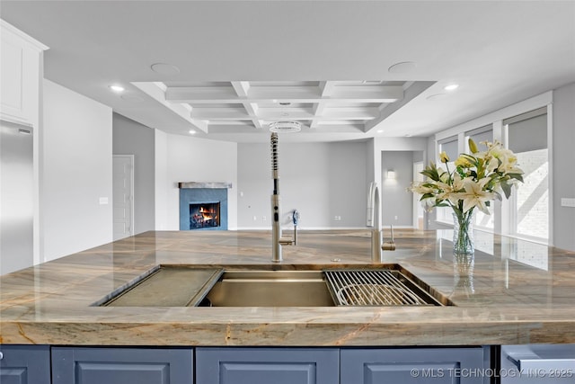 kitchen with coffered ceiling, recessed lighting, a lit fireplace, blue cabinets, and open floor plan