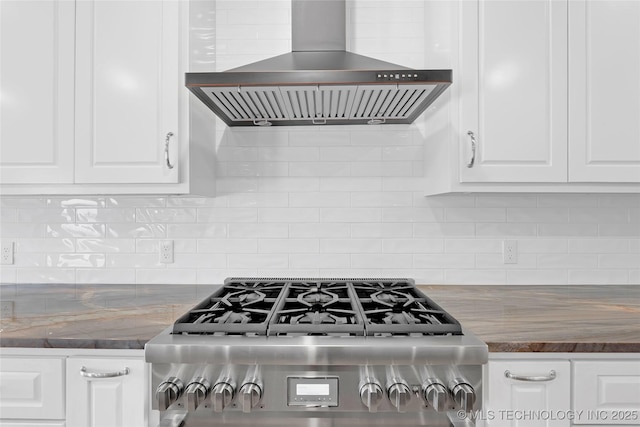 kitchen with gas range, backsplash, wall chimney exhaust hood, and white cabinetry