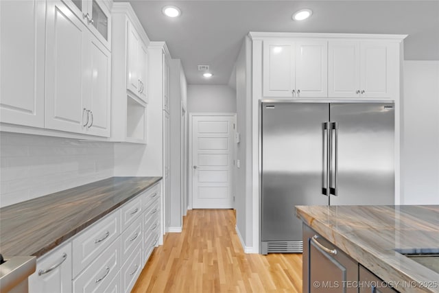 kitchen with light wood finished floors, recessed lighting, white cabinets, and built in fridge