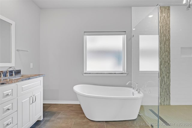 full bath with vanity, baseboards, tiled shower, a freestanding bath, and tile patterned floors