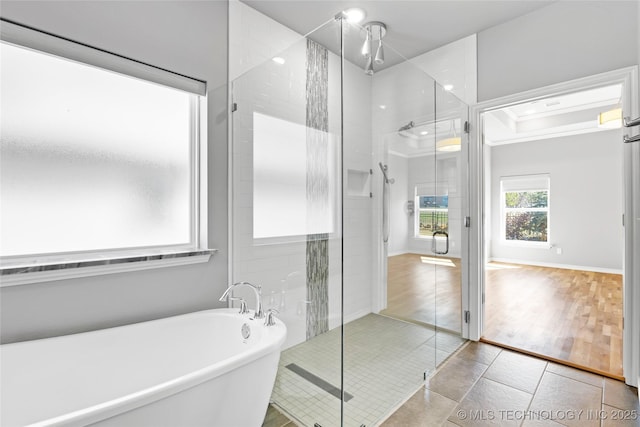 full bath featuring a freestanding tub, a shower stall, tile patterned flooring, crown molding, and baseboards