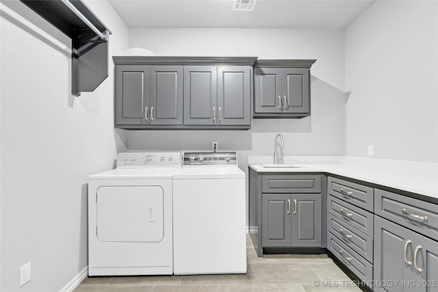 laundry area with visible vents, a sink, cabinet space, light tile patterned floors, and washing machine and clothes dryer