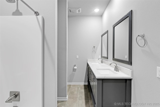 bathroom featuring tile patterned flooring, visible vents, walk in shower, and a sink