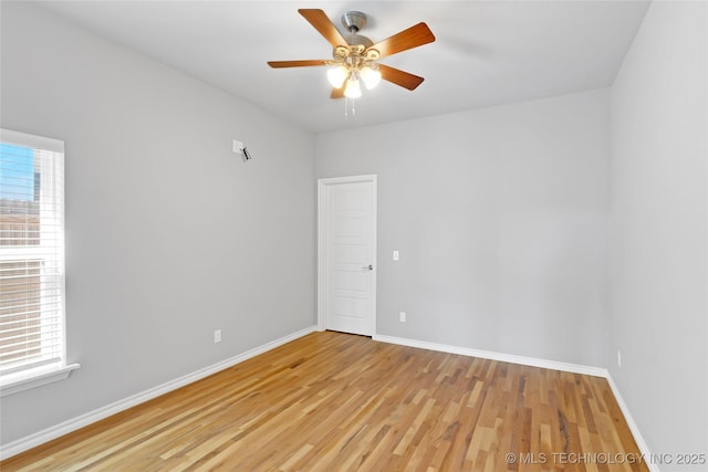 empty room featuring plenty of natural light, light wood-style flooring, a ceiling fan, and baseboards