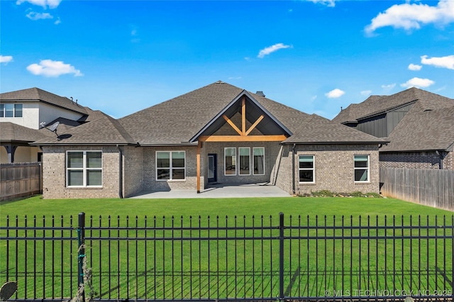 back of property featuring brick siding, a patio area, a lawn, and a fenced backyard