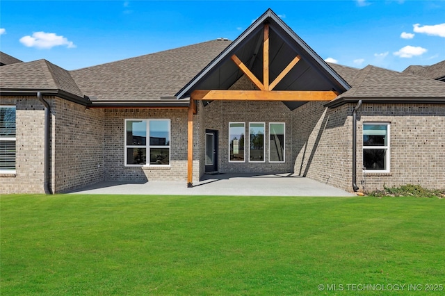 back of house with a patio, a lawn, brick siding, and roof with shingles