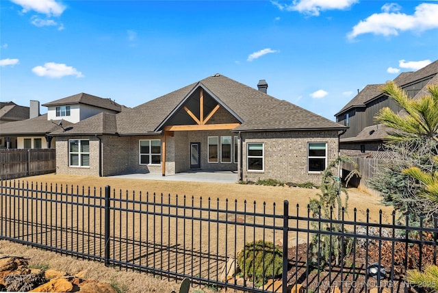 view of front facade featuring a patio area, brick siding, and a fenced backyard