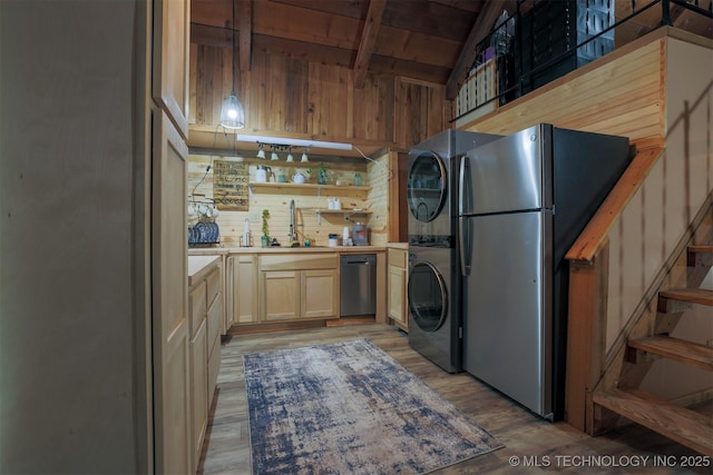 kitchen featuring open shelves, freestanding refrigerator, stacked washer and dryer, light wood-style floors, and dishwasher