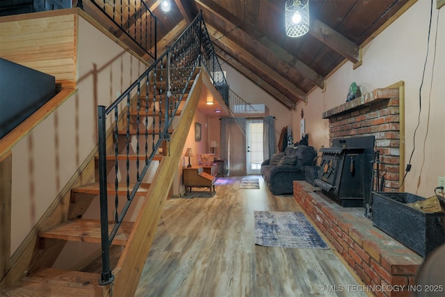 living area featuring beamed ceiling, high vaulted ceiling, wood finished floors, wood ceiling, and stairs