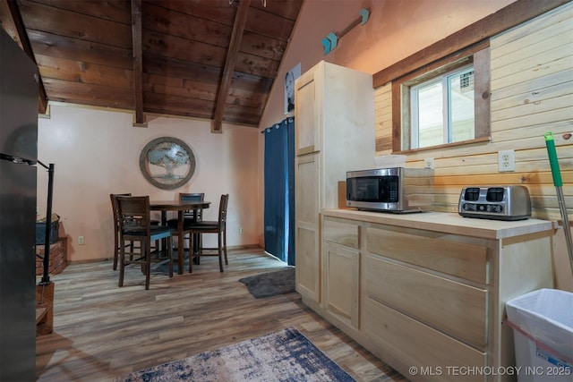 kitchen featuring light wood-type flooring, lofted ceiling with beams, stainless steel microwave, wooden ceiling, and light countertops