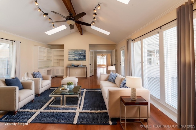 living room with baseboards, ceiling fan, lofted ceiling with skylight, ornamental molding, and wood finished floors