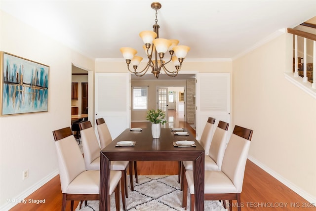 dining space with a notable chandelier, wood finished floors, baseboards, and ornamental molding