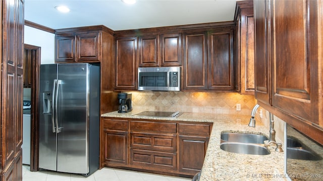 kitchen with a sink, decorative backsplash, light stone countertops, and appliances with stainless steel finishes