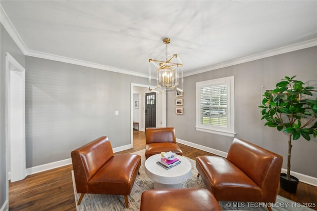 sitting room with a chandelier, crown molding, baseboards, and wood finished floors